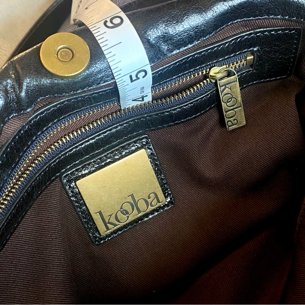 Kooba bag black leather.  3 signature zipper fobs, and 2 signature emblems.
